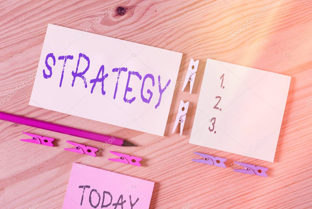 Word writing text Strategy. Business concept for action plan or strategy designed to achieve an overall goal Colored clothespin papers empty reminder wooden floor background office.
