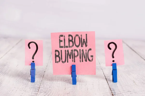 Elbow Bumping 의 텍스트 사인. 처음에 찍은 사진에는 눈 깜짝 할 사이에 악수를 하고 있었는데, 두 사람 이 나무 탁자 위에 종이 클립을 올려 놓은 채로 두 개의 손바닥에 스크리브하고 부스러지는 종이를 놓고 있었다. — 스톡 사진