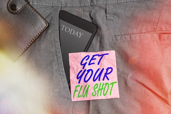 Text sign showing Get Your Flu Shot. Conceptual photo immunization is given yearly to protect against the influenza Smartphone device inside trousers front pocket with wallet and note paper.