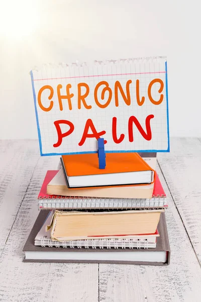 Text sign showing Chronic Pain. Conceptual photo discomfort that persists or progresses over a long period pile stacked books notebook pin clothespin colored reminder white wooden.