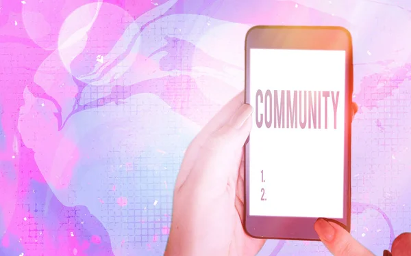 Word writing text Community. Business concept for group of showing with a common characteristics living together Modern gadgets with white display screen under colorful bokeh background.