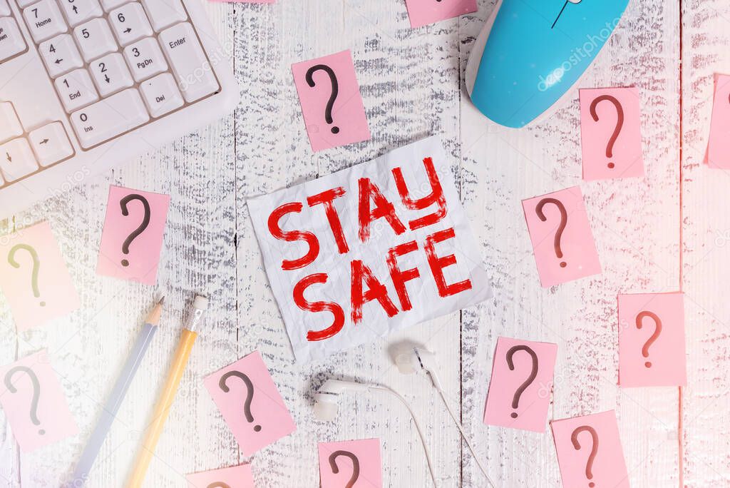 Text sign showing Stay Safe. Conceptual photo secure from threat of danger, harm or place to keep articles Writing tools, computer stuff and scribbled paper on top of wooden table.