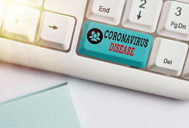 Coronavirus Hastalığı 'nın el yazısı. Yeni bir virüs olan SARSCoV2 beyaz pc klavyesinin beyaz tuş alanının üzerinde boş not kağıdı bulunan hastalık olarak tanımlanan kavram.