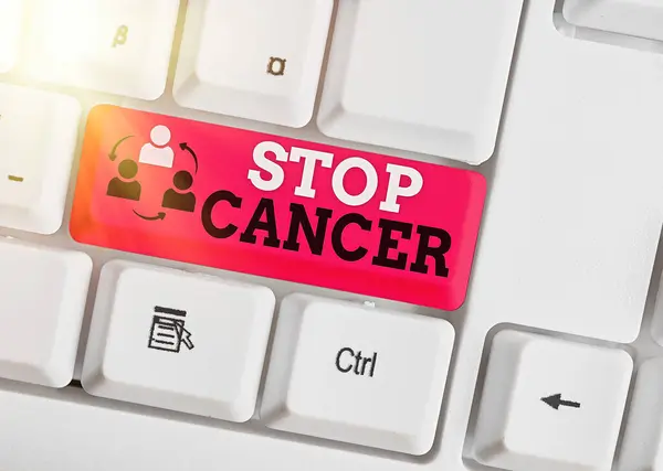 手書き文字起こし｜Stop Cancer。概念的な意味は、体内の異常な細胞の制御されていない成長を防ぐホワイトキーコピースペースの上に空のノート紙とホワイトPCキーボード. — ストック写真