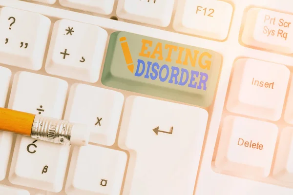 Conceptual hand writing showing Eating Disorder. Business photo text illnesses or severe disturbances in their eating behaviors White pc keyboard with empty note paper above white key copy space. — Stock Photo, Image