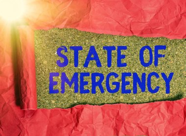 Olağanüstü Hal 'i gösteren kavramsal el yazısı. İş fotoğrafı metni, aşırı bir durumun ulusal düzeyde etkili olduğunu onaylıyor. Tahta klasik bir masanın üstünde yuvarlanmış yırtık bir karton..