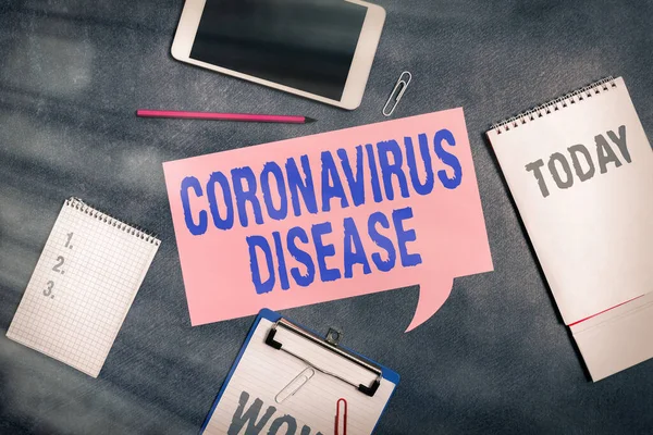 Слово писать текст Coronavirus Disease. Бизнес-концепция для определения болезни, вызванной новым вирусом SARSCoV2 Бумажные аксессуары с цифровым смартфоном расположены на другом фоне. — стоковое фото