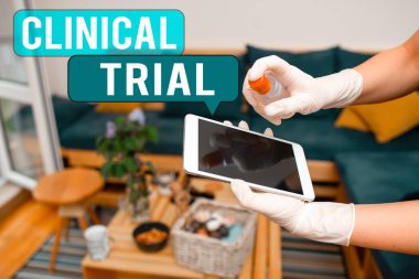 Klinik Deneme 'yi gösteren bir mesaj. Kavramsal fotoğraf, ilaçların etkinliğini ve güvenliğini dezenfektan tarafından kontrol edilen elektronik cihazlar içindeki kirliliği değerlendirir..