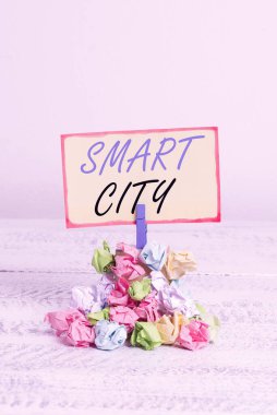 Smart City 'yi gösteren bir not yazıyorum. Bilgi toplamak için iletişim teknolojilerini kullanan kentsel bir alanı gösteren bir iş fotoğrafı. Renkli, buruşuk kağıt çamaşır mandalı yığını..