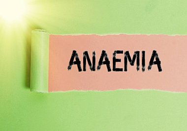 Anemi belirtileri var. Kavramsal fotoğraf, kanda hemoglobin eksikliğiyle işaretlenmiş yırtılmış karton, ahşap bir masa arkaplanının üzerine yerleştirilmiş..