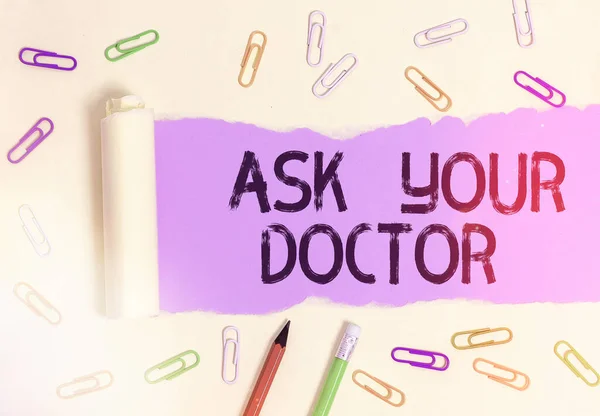 Writing note showing Ask Your Doctor. Business photo showcasing seeking information or advice from a medical professional Rolled ripped torn cardboard above a wooden classic table.