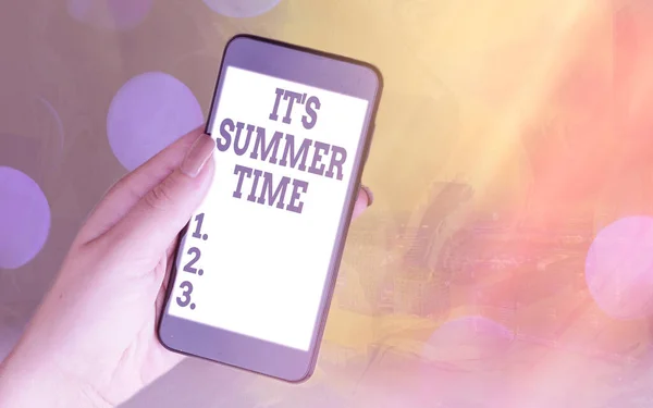 Rukopis Text Je letní čas. Koncept znamená sezónu pro zábavu a vzrušení těší slunné počasí Moderní gadgets s bílým displejem obrazovky pod barevné pozadí bokeh. — Stock fotografie