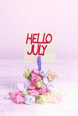 Kelime yazma metni Merhaba July. Gelecek tatil ayı için heyecan ifadesi konsepti. Renkli, buruşuk kağıt çamaşır tokası. Beyaz ahşap uzayı anımsatıyor..