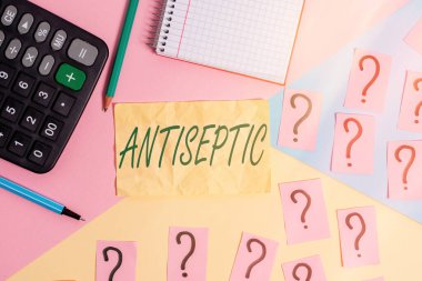 Antiseptiği gösteren bir not yazıyorum. Mikroorganizmayı geciktiren ya da tamamen ortadan kaldıran antimikrobiyal ajanları gösteren iş fotoğrafı. Matematik şeyleri ve pastel renklerin üzerine yazma ekipmanları.