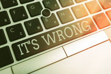 Yanlış olduğunu gösteren bir not yazıyorum. Arkaplan kopyalama alanının üzerinde boş not kağıdı ile eylem Pc klavye anahtarının yanlış, adaletsiz veya rencide edici tepkisini gösteren iş fotoğrafı.