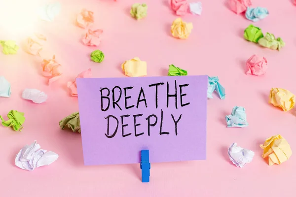 Handwriting text writing Breathe Deeply. Concept meaning to take a lot of air into the lungs inhaleexhale fully Colored crumpled papers empty reminder pink floor background clothespin.