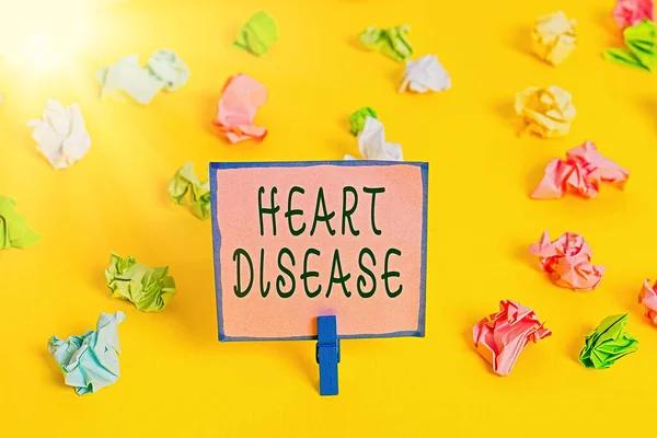 Word writing text Heart Disease. Business concept for A type of disease that affects the heart or blood vessels Colored crumpled papers empty reminder white floor background clothespin. — Stock Photo, Image