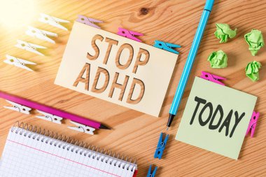 Kelime yazma metni Adhd dur. Bir çocuğun beynini ve davranışlarını etkileyen bir hastalığın tedavisinde kullanılan iş konsepti. Renkli çamaşır iğnesi kağıtları boş ahşap zemin ofisini anımsatıyor..
