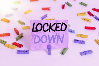 Locked Down 'ı gösteren bir not yazıyorum. Yasak bölgeye girilmesini engelleyen iş fotoğrafı görüntüleme acil durum önlemi: Renkli çamaşır iğnesi kağıtları boş hatırlatıcı beyaz zemin arka plan ofisi.