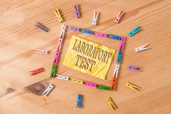 Writing note showing Laboratory Test. Business photo showcasing Determination of a medical diagnosis from the substances tested Colored clothespin papers empty reminder wooden floor background office.