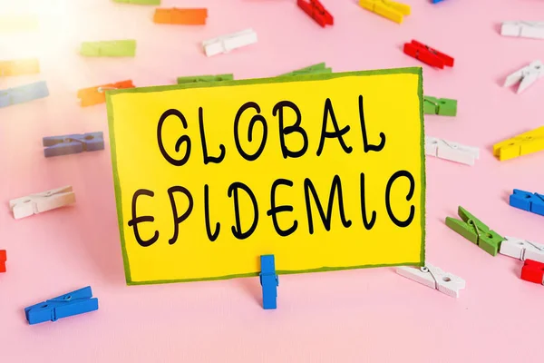 Word writing text Global Epidemic. Business concept for a rapid spread of a communicable disease over a wide geographic area Colored clothespin papers empty reminder pink floor background office pin.