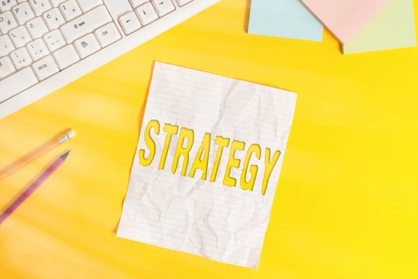 Texto de escritura de palabras Estrategia. Concepto de negocio para plan de acción o estrategia diseñado para lograr un objetivo general Copiar el espacio en el cuaderno sobre fondo amarillo con el teclado de la PC sobre la mesa . — Foto de Stock