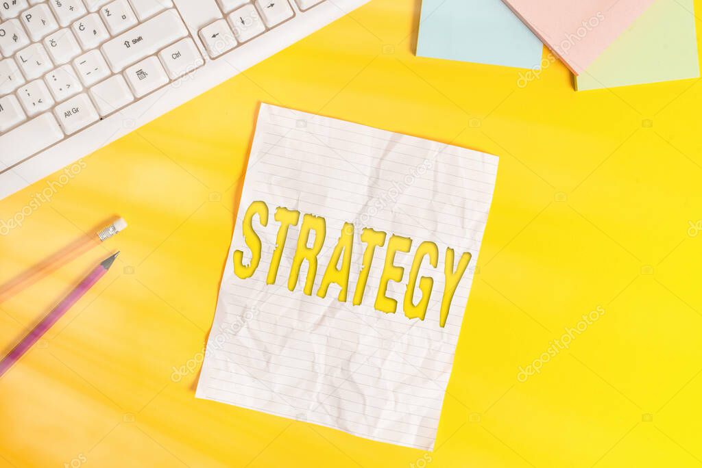 Word writing text Strategy. Business concept for action plan or strategy designed to achieve an overall goal Copy space on notebook above yellow background with pc keyboard on the table.