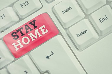 Evde Kal 'ı gösteren kavramsal el yazısı. İş fotoğrafı metni bir etkinlik için dışarı çıkmasın ve beyaz tuş alanının üzerinde boş not kağıdıyla ev veya ev içinde kalmasın.