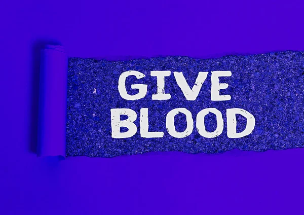 単語の執筆テキスト血を与えなさい。個人のためのビジネスの概念は自発的に血を引き、輸血のために使用される木製の古典的なテーブルの背景の上に置かれたロール引き裂かれた段ボール. — ストック写真