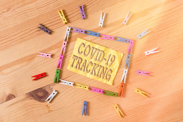 Writing note showing Covid 19 Tracking. Business photo showcasing Distinguishing process of the possible infected individuals Colored clothespin papers empty reminder wooden floor background office. — Stock Photo, Image