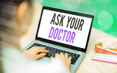 Doktoruna Sor 'u gösteren bir not yazıyorum. Ticari fotoğraf sergisi bilgi ya da tavsiye isteyen tıbbi profesyonel bir cihazdan renkli bokeh arkaplan altında beyaz ekran.