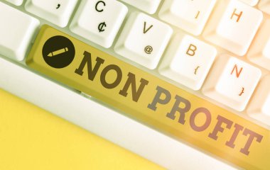 El yazısı Non Profit. Kavram, kar amacı gütmeyen veya yürütülmeyen bir etkinlik anlamına gelir. Boş kopya alanı üzerinde aksesuarlar düzenlenmiş farklı renkli klavye anahtarı.