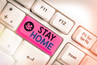 Kelime yazma metni Evde Kal. Bir etkinlik için dışarı çıkmak ve ev veya ev içinde kalmak için iş konsepti beyaz tuş kopya alanı üzerinde boş not kağıdı ile beyaz pc klavye.