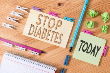 Kelime yazma metni Diyabet 'i durdurun. Kandaki yüksek glikoz seviyesini önlemek için iş konsepti. Renkli çamaşır iğnesi kağıtları boş ahşap zemin ofisini anımsatıyor..