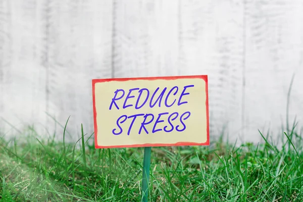 Writing note showing Reduce Stress. Business photo showcasing to lessen the state of mental or emotional strain or tension Plain paper attached to stick and placed in the grassy land.