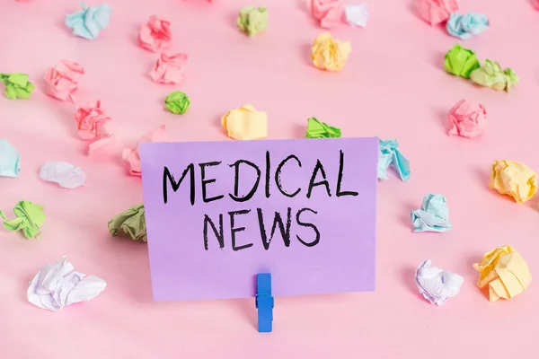 Handwriting text writing Medical News. Concept meaning report or noteworthy information on a medical breakthrough Colored crumpled papers empty reminder pink floor background clothespin.