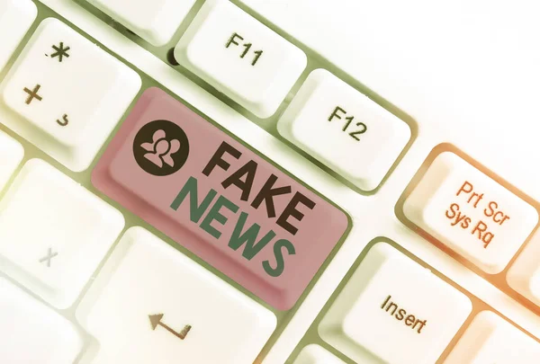 Píšu text Fake News. Obchodní koncept pro falešné informace publikovat pod rouškou autentických novinek Bílá PC klávesnice s prázdným poznámkovým papírem nad bílou klávesou kopírovat prostor. — Stock fotografie