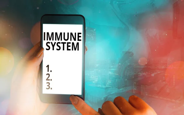 Handwriting text Immune System. Concept meaning a bodily system that protects the body from foreign substances Modern gadgets with white display screen under colorful bokeh background.