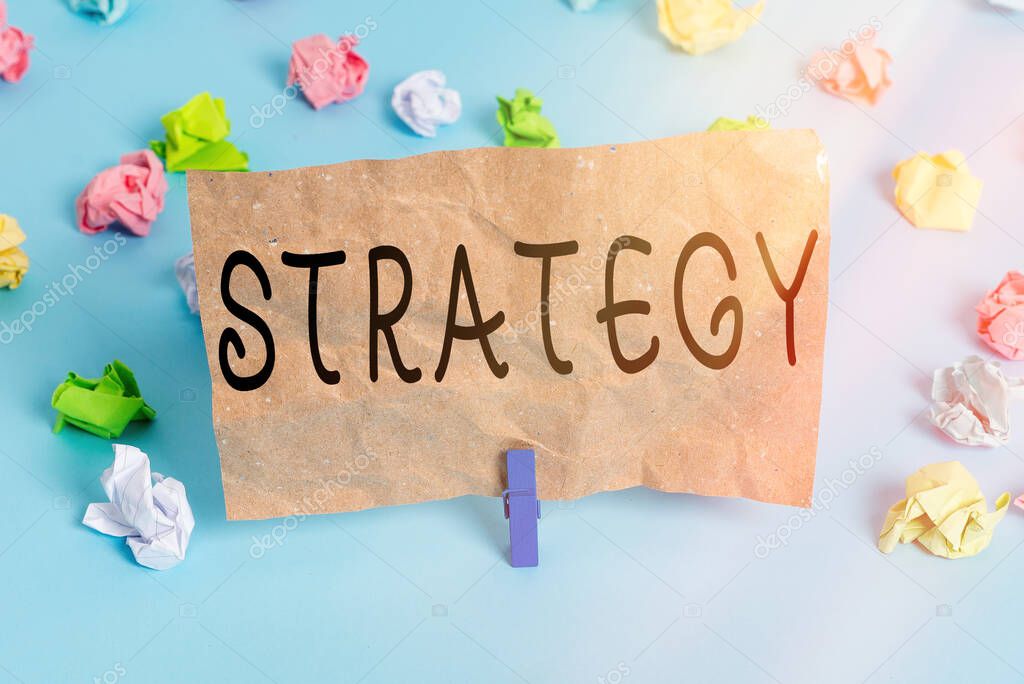 Text sign showing Strategy. Conceptual photo action plan or strategy designed to achieve an overall goal Colored crumpled papers empty reminder blue floor background clothespin.
