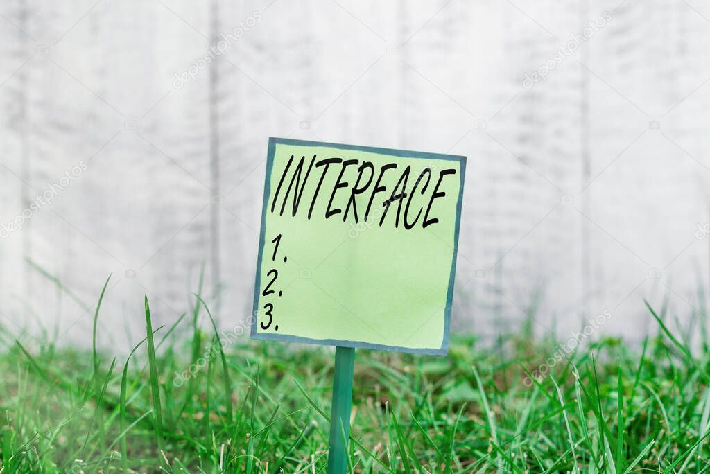 Conceptual hand writing showing Interface. Business photo showcasing point of meeting and communicating between two structures Plain paper attached to stick and placed in the grassy land.