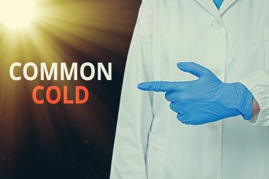 Kelime yazma metni Common Cold. Üst solunum yolundaki viral enfeksiyon için iş konsepti öncelikle burnu etkileyen boş kağıt aksesuarları gösteren tıbbi eldivenlerle akıllı telefon..