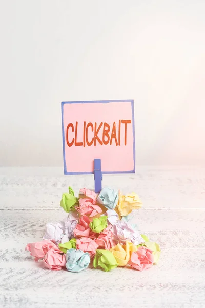 Tekstbord met Clickbait erop. Conceptuele foto het belangrijkste doel is om de aandacht te vestigen op een bepaalde webpagina Herinnering stapel gekleurde verfrommeld papier wasknijper herinnering witte houten ruimte. — Stockfoto