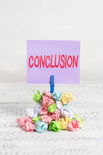 Word writing text Conclusion. Business concept for used at the end of a speech of writing to make final comments Reminder pile colored crumpled paper clothespin reminder white wooden space.