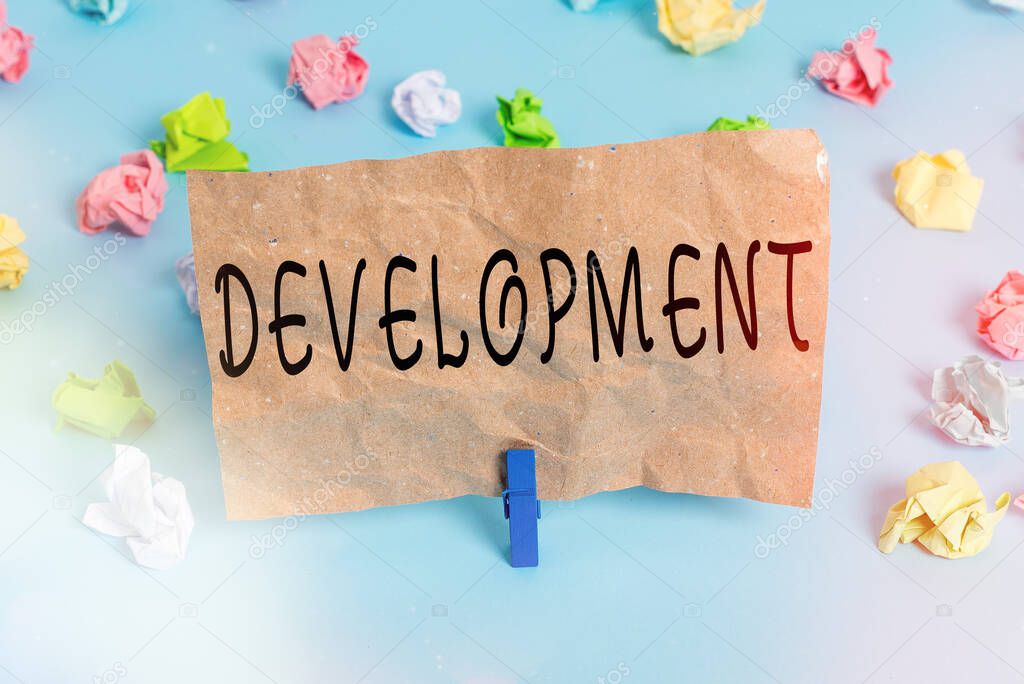 Text sign showing Development. Conceptual photo a cycle in which somebody or something grows or changes Colored crumpled papers empty reminder blue floor background clothespin.