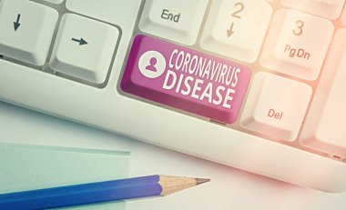 Coronavirus Hastalığı 'nı gösteren bir not yazıyorum. İş fotoğrafı gösterimi, yeni bir virüs olan SARSCoV2 'nin neden olduğu hastalık olarak tanımlanır. Boş kopya alanındaki aksesuarlarla donatılmış klavye anahtarı.