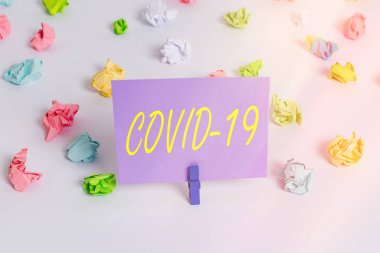 Covid19 'un el yazısı. Coronavirus 'un sebep olduğu hafif ya da ağır solunum hastalığının kavramı. Renkli buruşmuş kağıtlar. Boş hatırlatıcı beyaz zemin çamaşır mandalı..