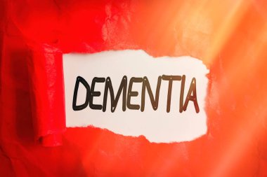 Bunamayı gösteren kavramsal el yazısı. İş fotoğrafı, hastalıklar ve rahatsızlıklar için kullanılan genel sözcüğü hafızasında bir kaybı olan yırtık kartonu ahşap klasik bir masanın üzerine yuvarlamış..