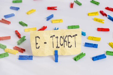 E-bileti yazan el yazısı. Konsept derken, detayların elektronik olarak kaydedildiği uçuş rezervasyonu. Renkli çamaşır iğnesi kağıtları boş hatırlatıcı beyaz zemin arkaplan ofisi.