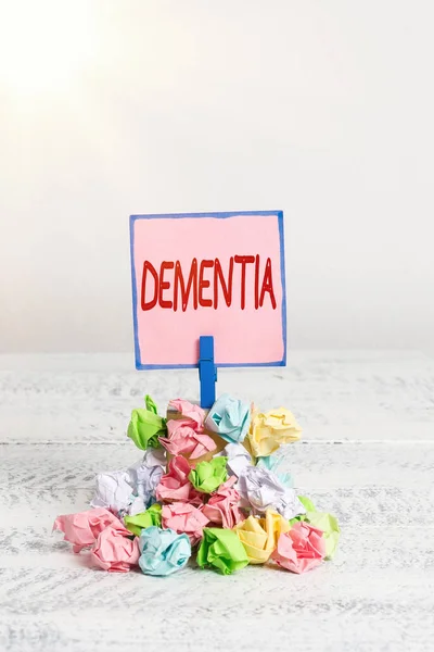 Text sign showing Dementia. Conceptual photo the general word for diseases and disorders with a loss in memory Reminder pile colored crumpled paper clothespin reminder white wooden space. — Stock Photo, Image