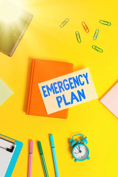 Text sign showing Emergency Plan. Conceptual photo instructions that outlines what workers should do in danger Flat lay above table with copy space paper clips clock and pencils.